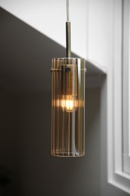 Tibia Ø7 Amber/messing raamlamp Van Markslöjd - Raamlamp met een cilindrische vorm, gecanneleerd amberkleurig glas en elegante messing details - een warm en decoratief ontwerp dat een zachte, sfeervolle gloed in het raam geeft.