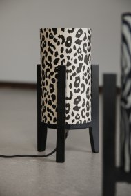 Eruca 34cm Luipaard tafellamp Van Markslöjd - De lampvoet van zwart hout is gecombineerd met een cilindrische textielen kap in gebroken wit en bruin luipaardpatroon, wat de lamp een trendy en persoonlijk karakter geeft.