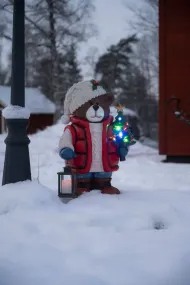 Grote Teddybeer 66cm Veelkleurig Van Konstsmide - Er staat een felverlichte kerstboom en een lantaarn in, wat voor een gezellige sfeer zorgt.