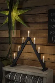 Candelabra 7 Lights Zwart Van Konstsmide - Opvouwbare elektrische kandelaar met 7 kaarsen, gemaakt van zwart geverfd hout, versierd met messing ringen rond elke kaars voor een elegante toets.