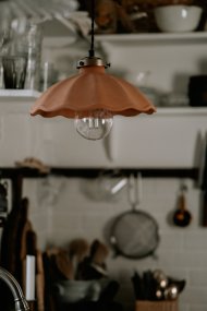 Alva Ø30 Terracotta hanglamp Van Globen Lighting - Het bovenste gedeelte dat het keramiek omsluit, is gemaakt van metaal in de kleur antiek messing en wordt gecombineerd met een 120 cm lange, zwarte, gedraaide textielkabel en een zwarte plafondkap van kunststof.