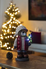 Kleine Teddybeer 38cm Veelkleurig Van Konstsmide - Er staat een felverlichte kerstboom en een lantaarn in, wat voor een gezellige sfeer zorgt.