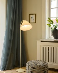 Medina Crème wit vloerlamp Van Halo Design - Het crèmekleurige metalen frame wordt aangevuld door een prachtige geplooide textielen kap in een bijpassende tint en decoratieve details van messing.