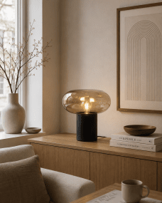 Alba 32cm Zwart/amber tafellamp Van Nordic Lighting - De zwarte metalen voet zorgt voor een stabiele en elegante uitstraling, terwijl de amberkleurige glazen kap een zacht en sfeervol licht cre&euml;ert.