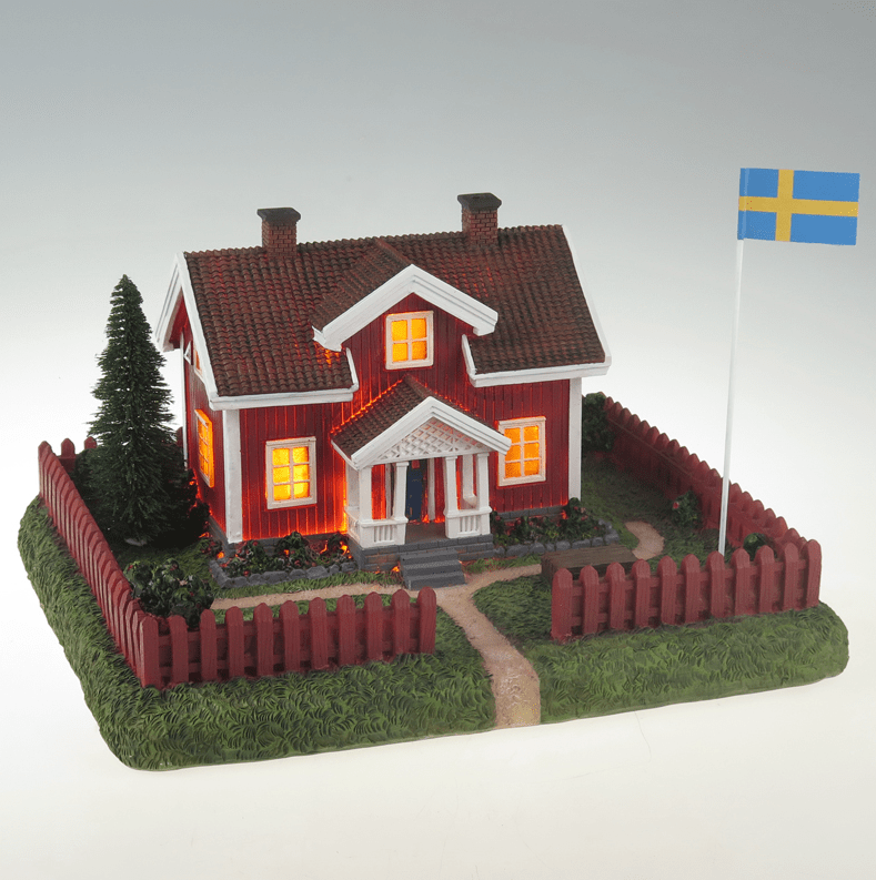 Sommarby ROOD Van Pixie Design - "Het Rode Huisje in de Zomer" - is een decoratieve verlichtingsarmatuur van keramiek die een klassiek Zweeds zomerhuisje met omliggende tuin en vlaggenmast voorstelt.