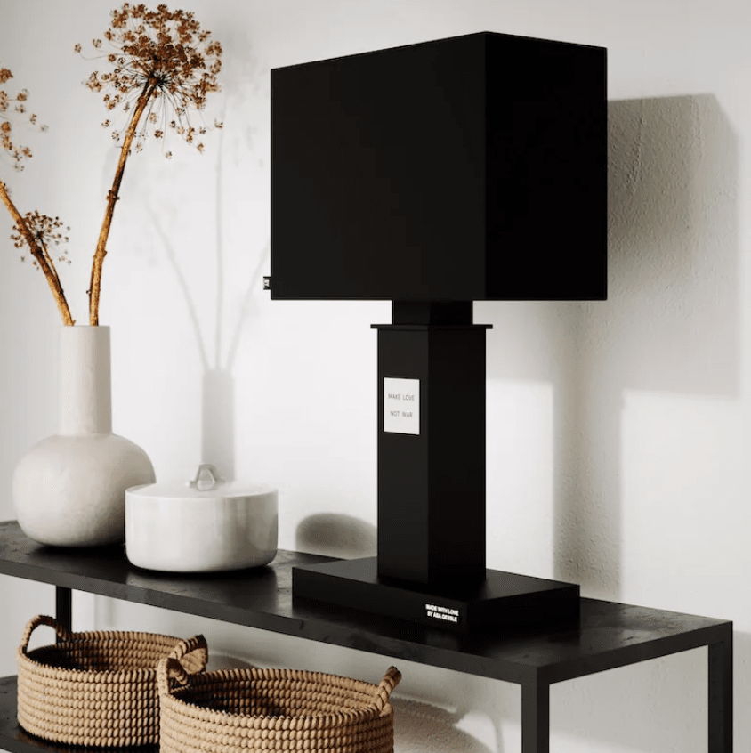 In Love 56cm Zwart tafellamp Van By Rydéns - De brede, zwarte stoffen lampenkap vormt een mooi contrast met de smalle lampenvoet, die versierd is met een metalen bord met de tekst &rdquo;Make love, not war&rdquo;.