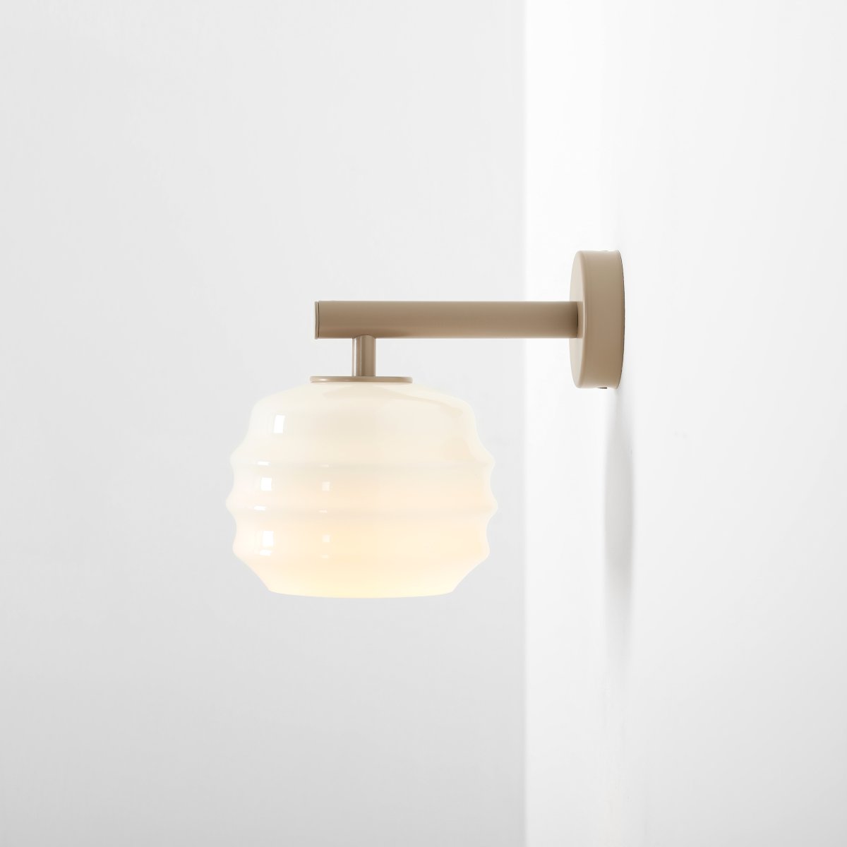 Puff 23cm Beige wandlamp Van Artera - De beige metalen details vormen een mooi contrast met het lichte glas en geven de lamp een warme uitstraling.