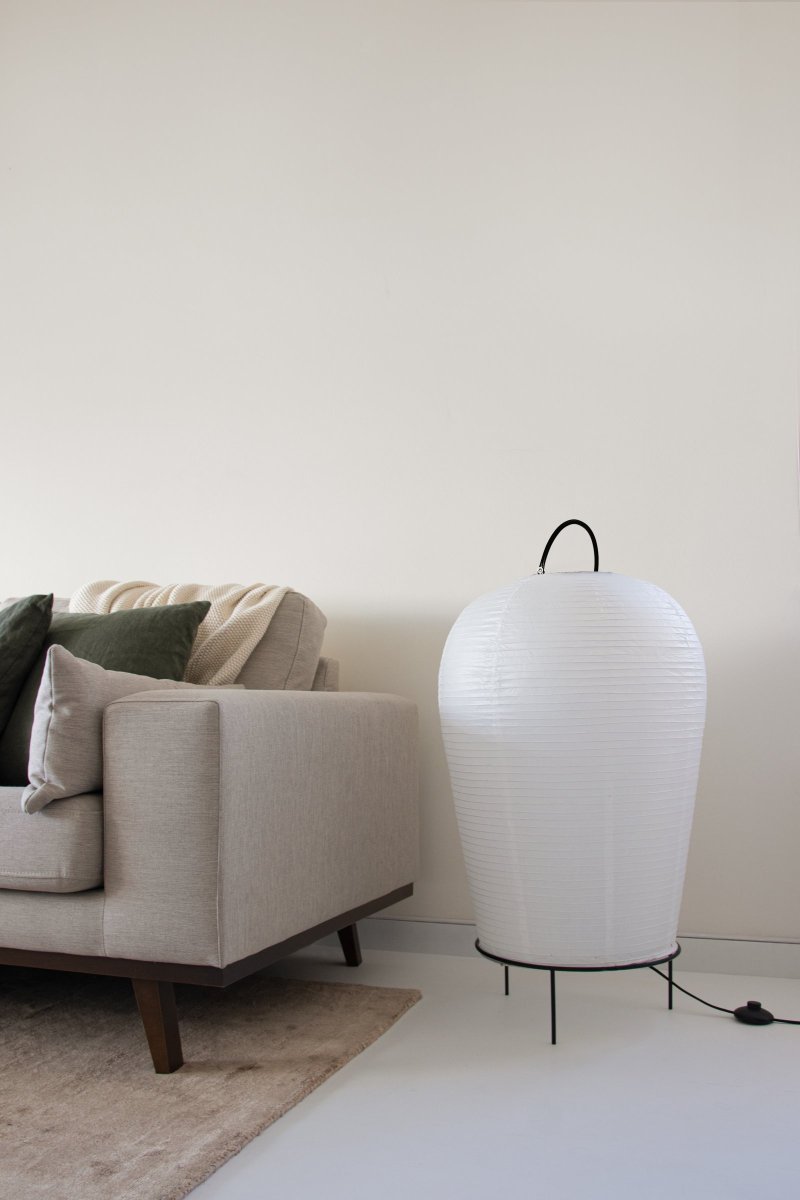 Osaka Wit vloerlamp Van Globen Lighting - De lamp is gemaakt van wit rijstpapier en heeft een decoratief handvat van matzwart gelakt metaal en een bijpassende standaard aan de onderkant waarop de papieren kap rust.