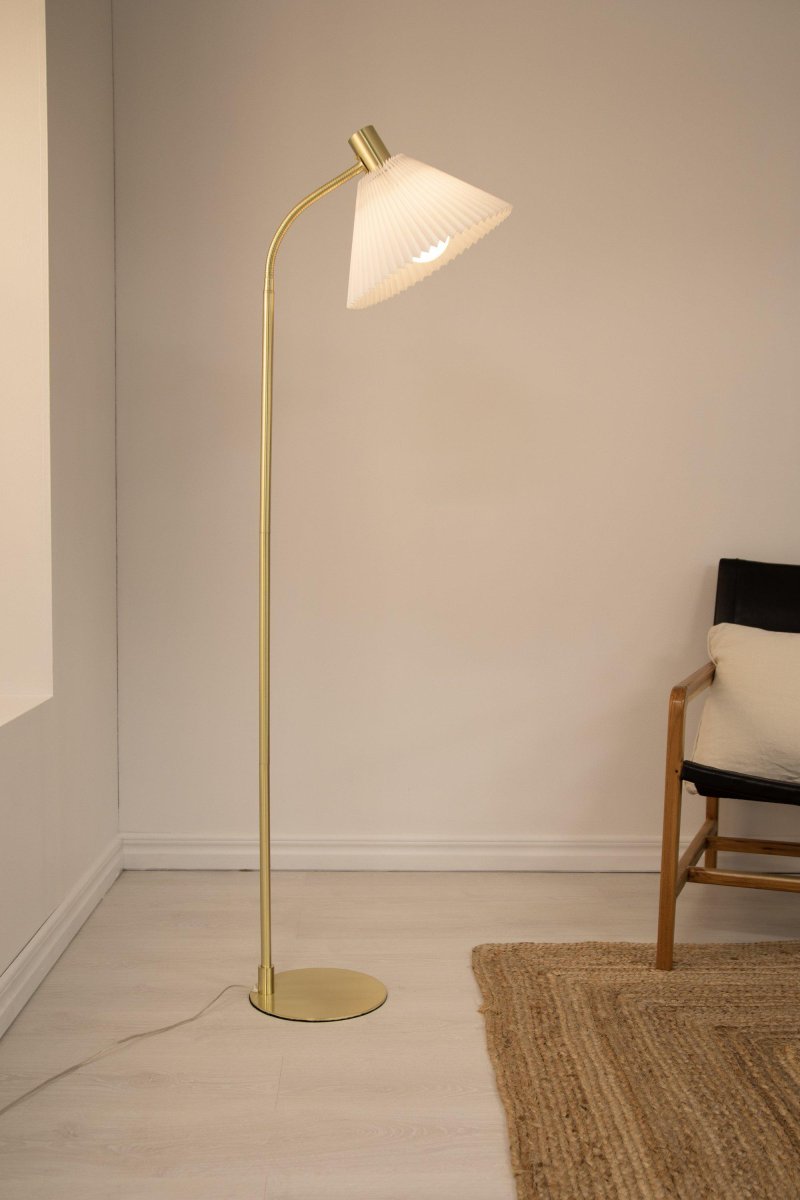 Mira Geborsteld messing vloerlamp Van Markslöjd - De Mira vloerlamp is 145 cm hoog, heeft een messingkleurige metalen lampenvoet en een geplooide lampenkap in witte stof.