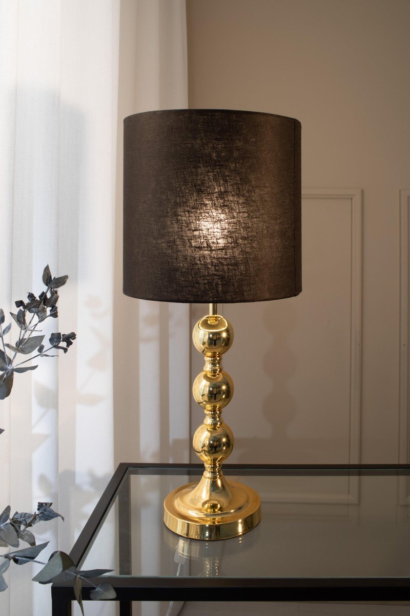 Octo 57cm Messing tafellamp Van Markslöjd - Octo is een elegante tafellamp met een zwarte linnen kap en een messingkleurige lampenvoet in de vorm van drie zachte, ronde bollen.