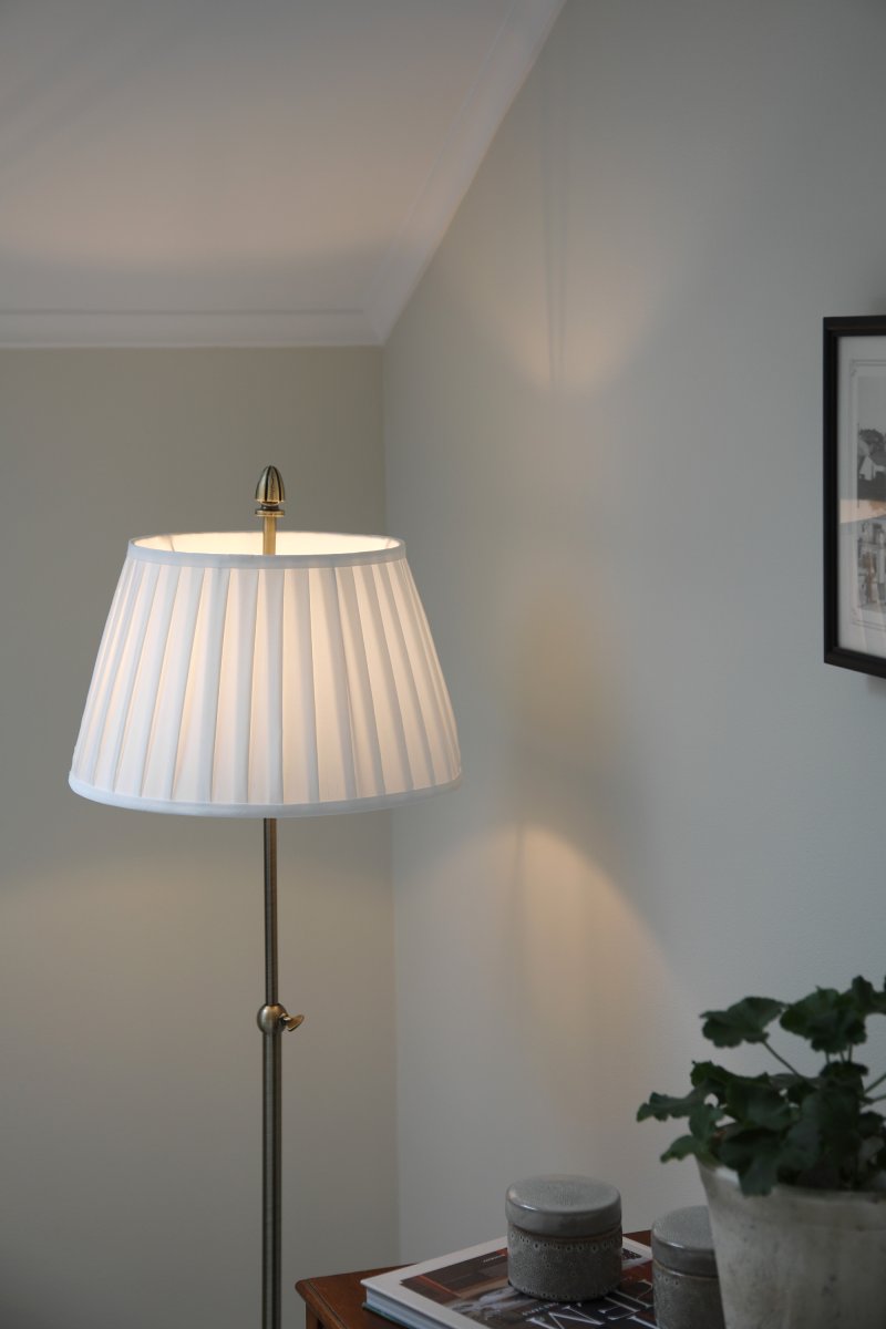 Oxford Antiek messing vloerlamp Van Markslöjd - Staande lamp in klassieke stijl van rond de eeuwwisseling met een gebroken witte stoffen kap en een voet met een antiek messing afwerking.