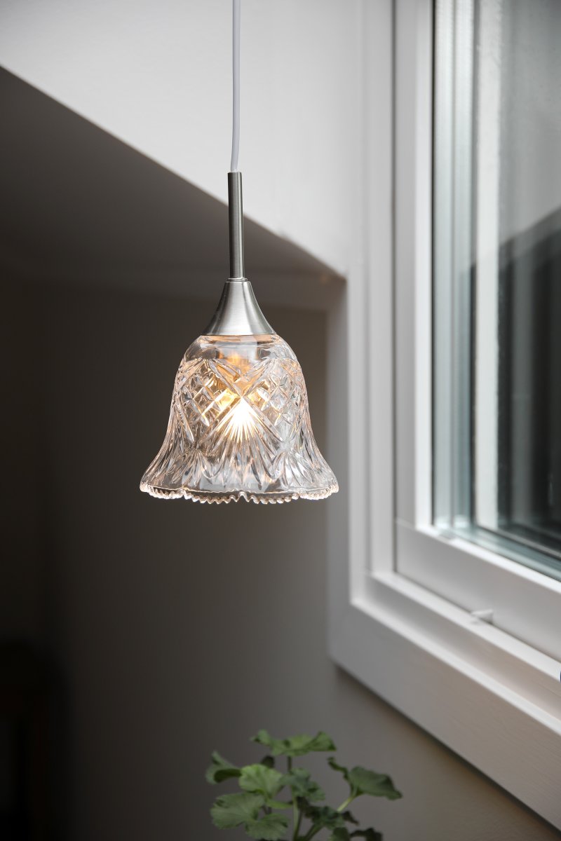 Luna Ø14 Transparant/staal raamlamp Van Markslöjd - Raamlamp van transparant glas met fijne details in satijnnikkelafwerking en een decoratieve, zacht gebogen vorm aan de onderkant - een romantisch ontwerp dat een warme en gastvrije sfeer creëert in het raam of in een klein hoekje.