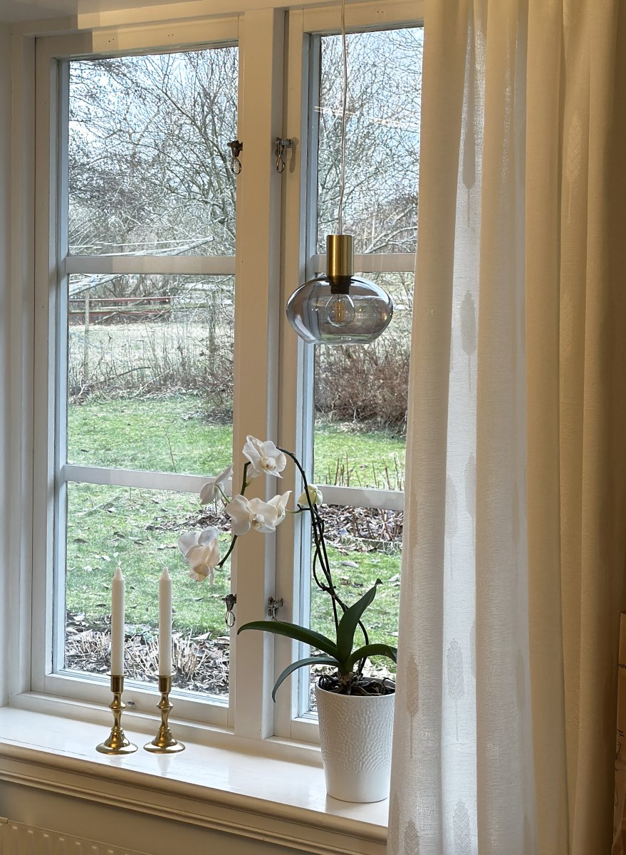 Bell Ø15 Rookkleurig raamlamp Van Aneta Lighting - Gemaakt van metaal met een matte messing afwerking en een ronde kap van rookglas die een zachte en aangename gloed verspreidt.