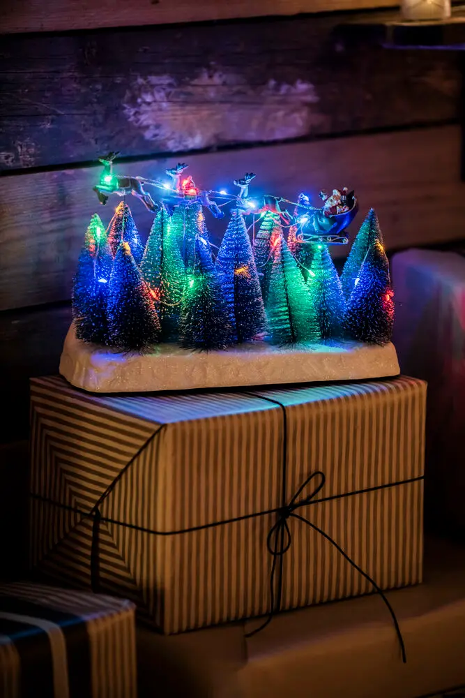 Kerstman Met Slee 22cm Veelkleurig Van Konstsmide - Kerstversiering met de Kerstman in een slee die over besneeuwde sparrenbomen vliegt.