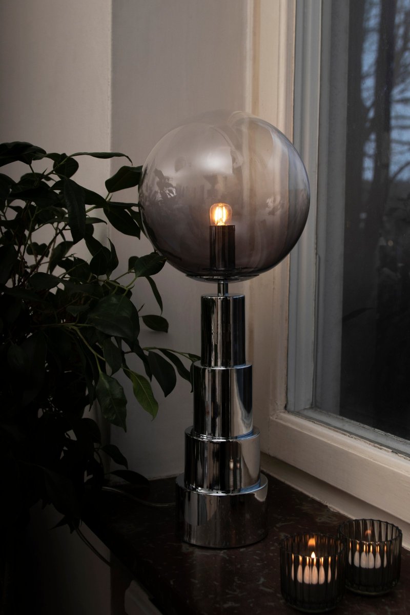 Astro 48cm Chroom tafellamp Van Globen Lighting - De lamp is gemaakt van chroomkleurig metaal en heeft een glazen bol die is getint van rookkleurig naar helder.
