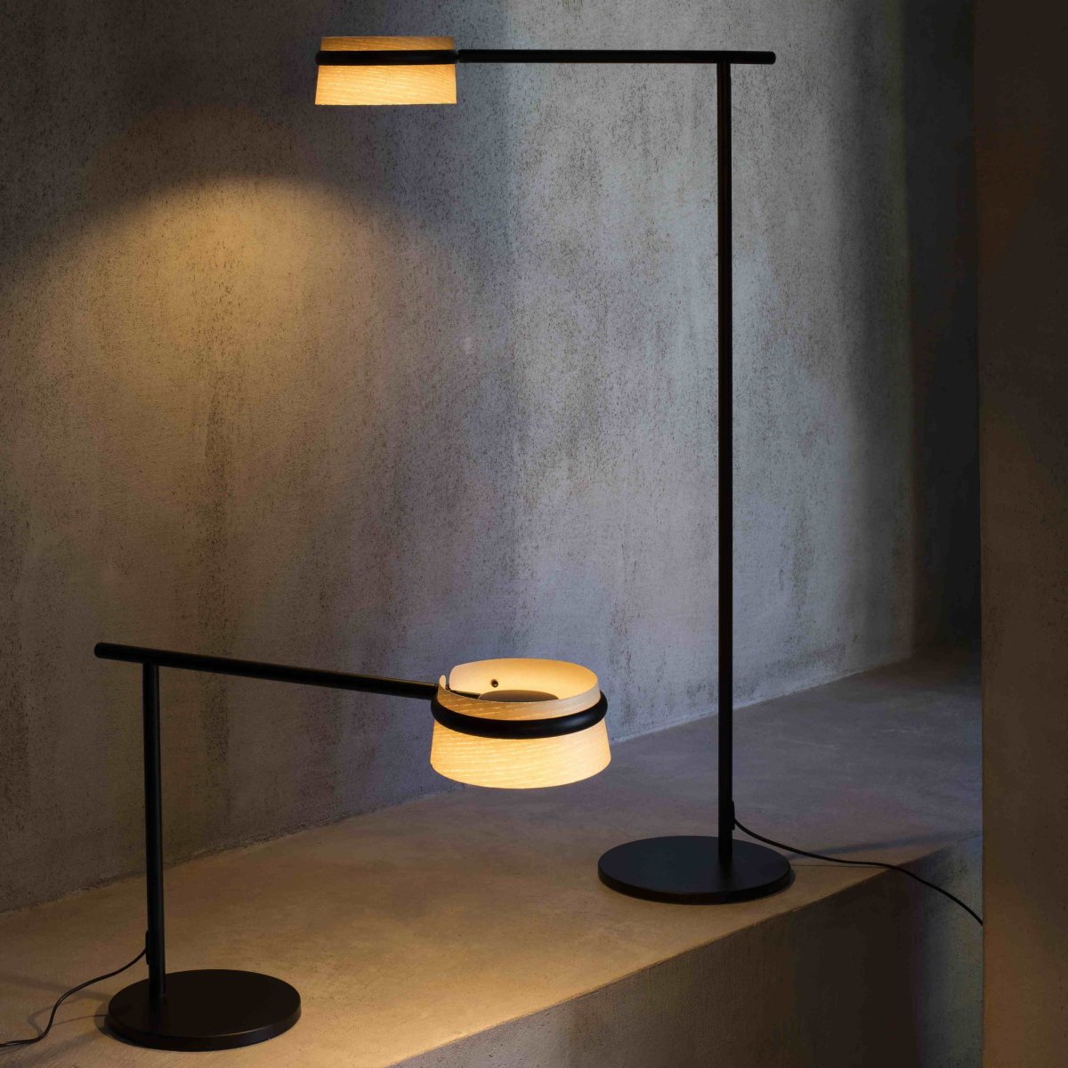 Loop Hout vloerlamp Van Faro Barcelona - De staande lamp kenmerkt zich door zijn rechte hoek, een ronde metalen voet en een elegante arm die een essenhouten kap omsluit.