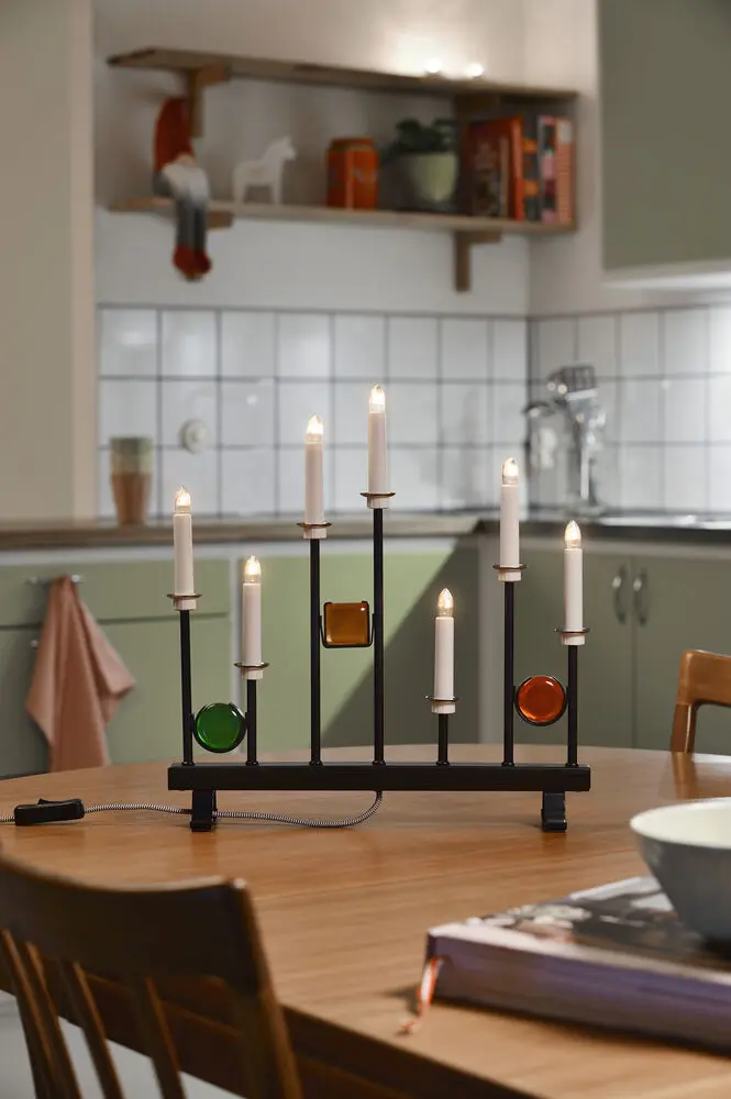 Candelabra 7 Lights Zwart Van Konstsmide - De zeven kaarsen zijn omlijst met decoratieve gekleurde glazen details in groen, rood en amber, waardoor een elegante en feestelijke sfeer ontstaat.