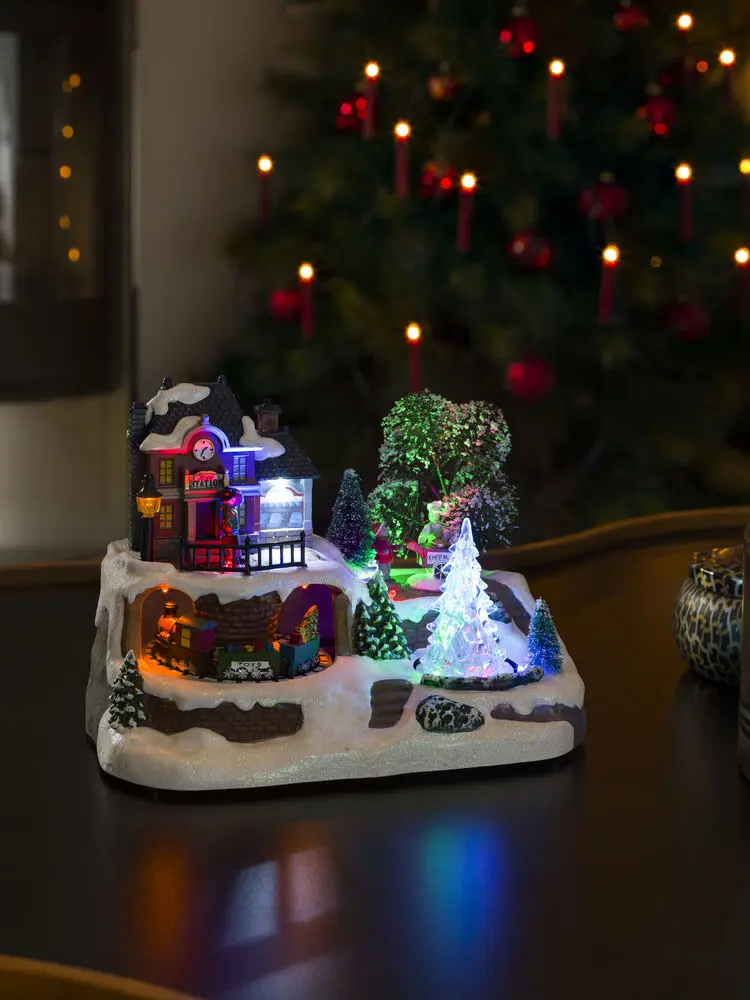 Mechanische Kerstdecoratie Met Treinstation 17cm Veelkleurig Van Konstsmide - Stap in een winterse miniatuurwereld met deze mechanische kerstversiering &ndash; een charmant treinstation in een besneeuwde omgeving.