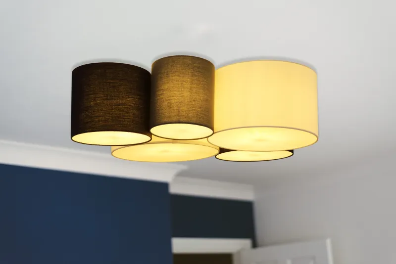 Makki 90cm Veelkleurig plafondlamp Van Globo Lighting - Lampan har en unik design med fem cylindriska textilsk&auml;rmar i olika storlekar, varav tv&aring; &auml;r vita, tv&aring; svarta och en gr&aring;.