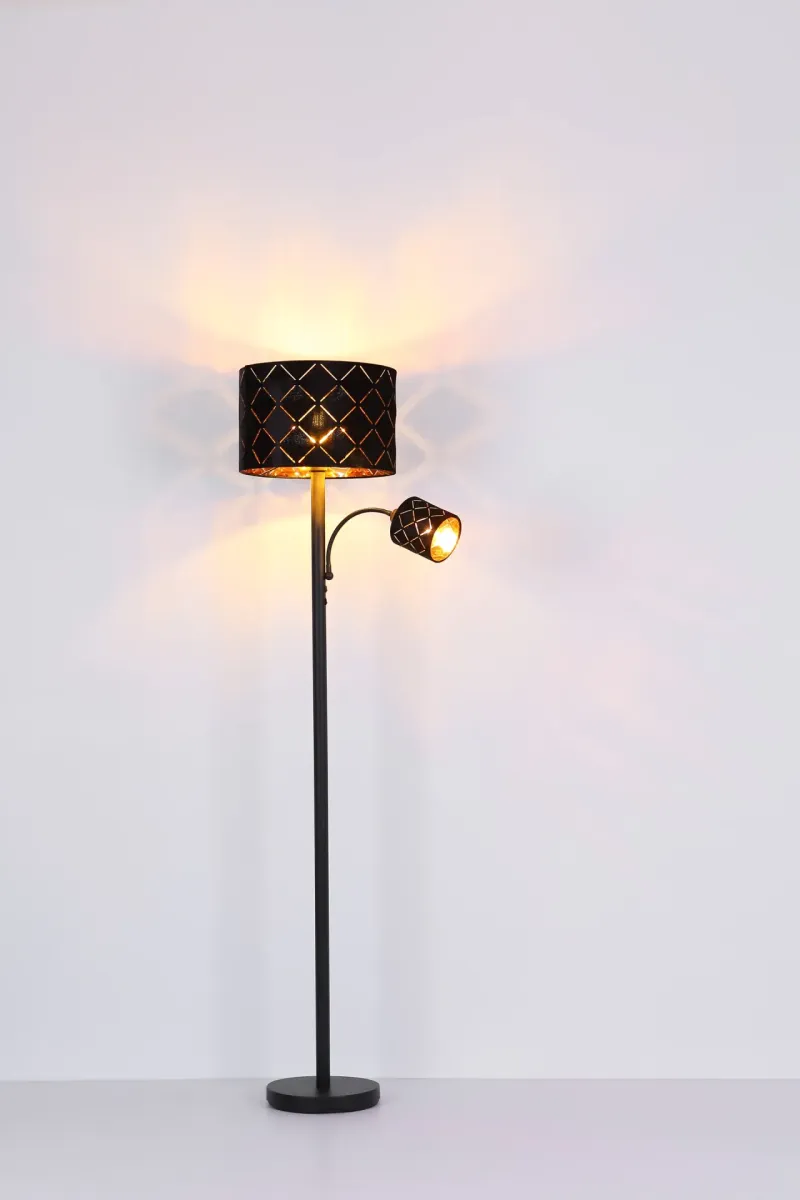 Sunna Zwart vloerlamp Van Globo Lighting - Den runda stommen i h&ouml;gkvalitativ svart metall ger stabilitet och tidl&ouml;s charm, medan den svarta lampsk&auml;rmen i sammet med dekorativa utsk&auml;rningar tillf&ouml;r en lyxig k&auml;nsla och skapar ett fascinerande ljusspel.