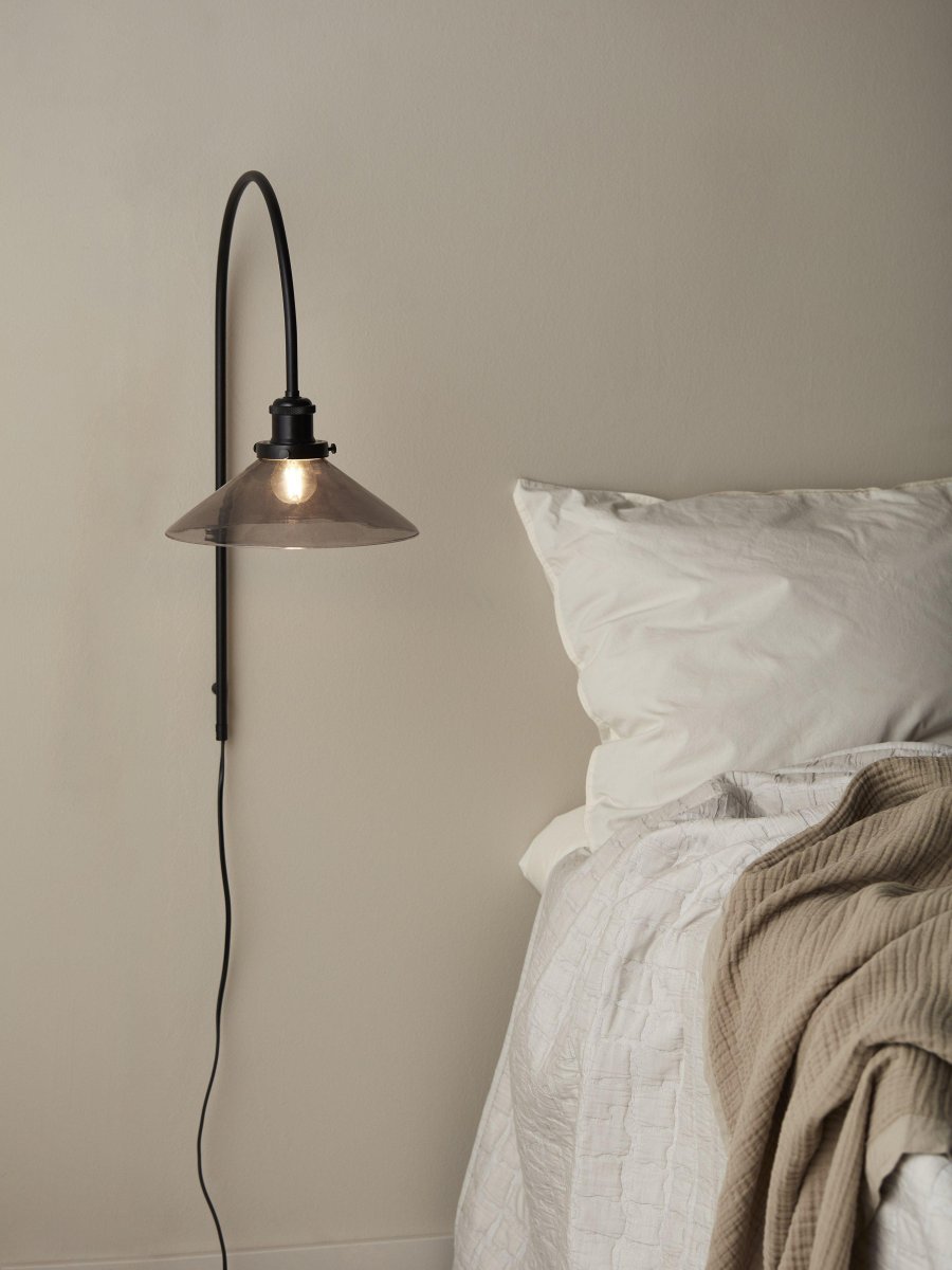 August 25cm Zwart wandlamp Van PR Home - De glazen kap heeft een zwarte afwerking en is bevestigd aan een lampenhouder van zwart geborsteld metaal.