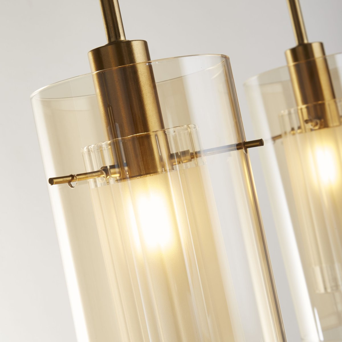 Duo 70cm Bronzen hanglamp Van Searchlight - De lamp is gemaakt van metaal met een stijlvolle bronzen afwerking en heeft drie cilindrische glazen kappen van amberkleurig glas.