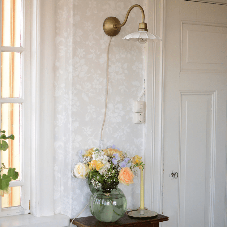 Gustav Ø20 Wit/antiek messing wandlamp Van Strömshaga - De antieke messing afwerking is gecombineerd met een wit gelakte metalen kap met een prachtig golvende rand, wat een zachte en stijlvolle uitstraling geeft.