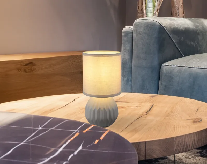 Sylas 23cm Grijs tafellamp Van Globo Lighting - Den rundade keramiska basen i elegant gr&aring;tt och den matchande cylindriska textilsk&auml;rmen skapar en harmonisk och modern estetik.