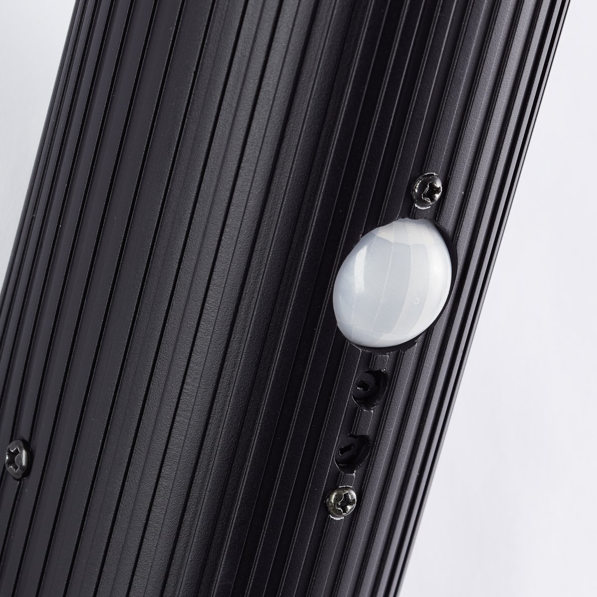 Cassio Zwart buitenlamp Van Brilliant - De langwerpige vorm en de combinatie van een zwarte geribbelde voet en een witte diffuser geven Cassio een elegante uitstraling die past bij verschillende gevelstijlen.