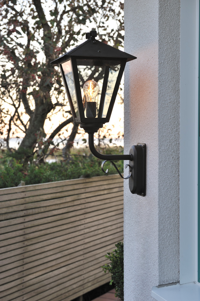 Benu Zwart buitenlamp Van Konstsmide - De klassieke lantaarnvorm en de robuuste materialen van de lamp maken hem tot een perfecte keuze voor wie een uitnodigende sfeer wil cre&euml;ren in entrees of lange gangen.