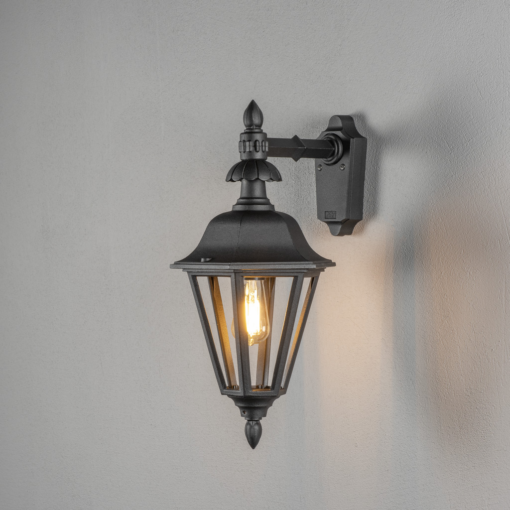 Pallas Zwart buitenlamp Van Konstsmide - Dankzij het lantaarnvormige ontwerp en de heldere glaspanelen verspreidt de lamp een warm en uitnodigend licht dat perfect is voor entrees, terrassen en looppaden.