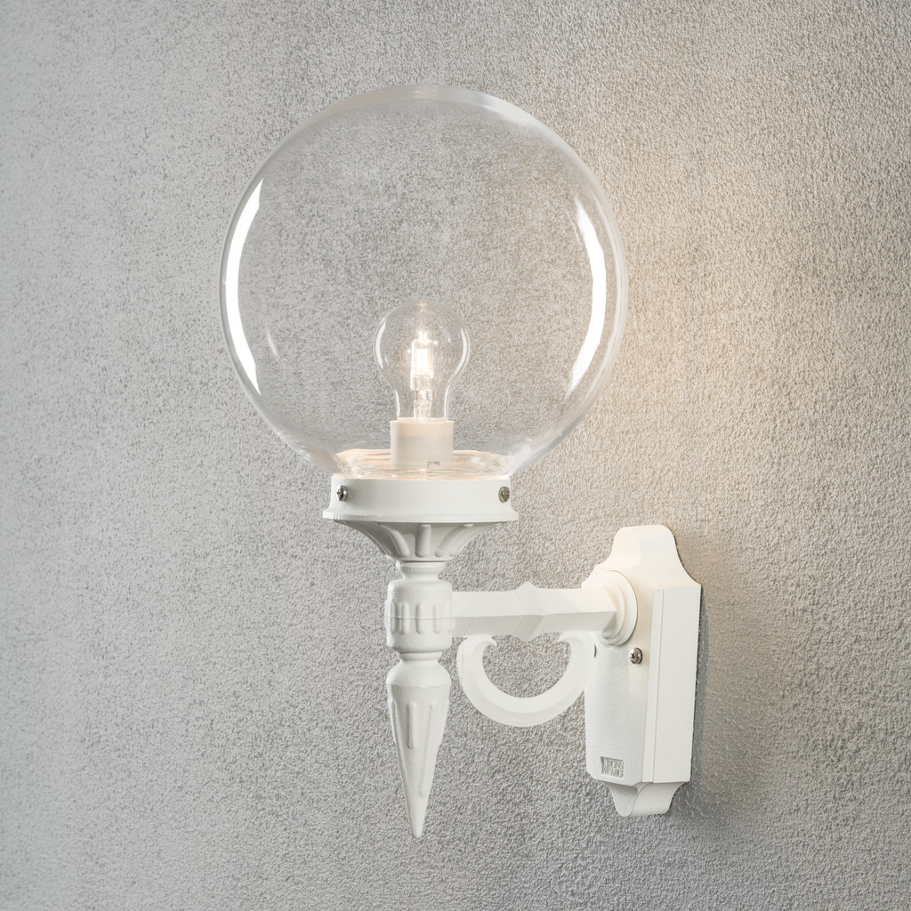 Orion Wit buitenlamp Van Konstsmide - Met zijn decoratieve details en tijdloze stijl wordt deze wandlamp een elegant detail dat uw gevel verfraait en een uitnodigende sfeer creëert.