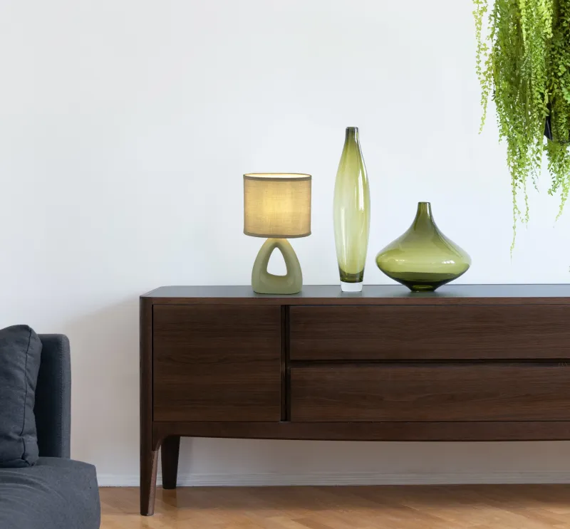Triangle 30cm Groente tafellamp Van Globo Lighting - Den triangelformade basen med ett stilrent utskuret h&aring;l ger ett modernt intryck, medan den ovala textilsk&auml;rmen i mjuk ljusgr&ouml;n f&auml;rg sprider ett behagligt och j&auml;mnt ljus.