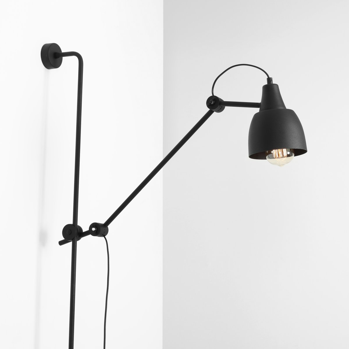 Dron 113cm Zwart wandlamp Van Artera - De matte zwarte afwerking geeft de lamp een industriële en verfijnde uitstraling, terwijl de verstelbare arm maximale flexibiliteit biedt om het licht te richten waar u het nodig hebt.