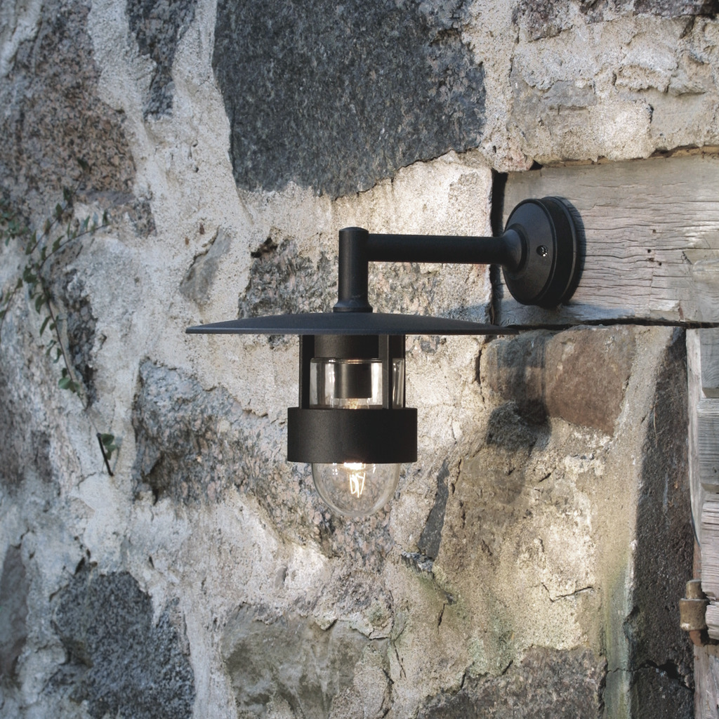 Freja Zwart buitenlamp Van Konstsmide - De lamp verspreidt een aangenaam licht door de glazen details en heeft een brede kap die bescherming biedt tegen weersinvloeden, waardoor de lamp zowel duurzaam als functioneel is.