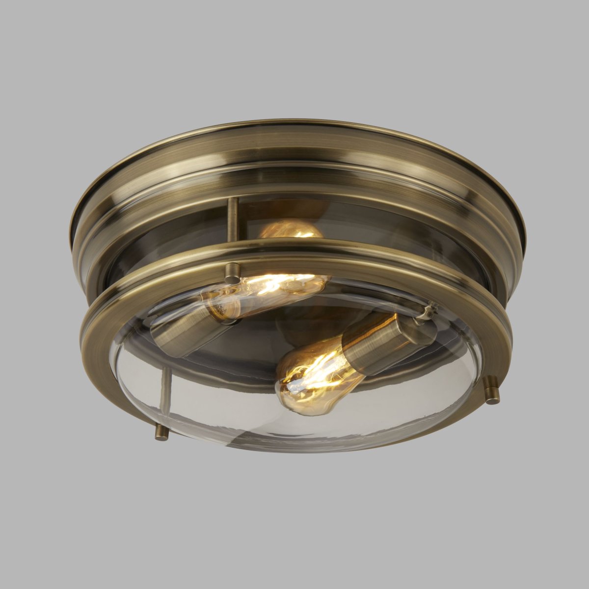 Glasgow Ø35 Antiek messing badkamerlamp Van Searchlight - De lamp combineert een robuust design met stijlvolle functionaliteit en verspreidt een warm, uitnodigend licht dankzij de zichtbare gloeilampen en de kap van helder glas.