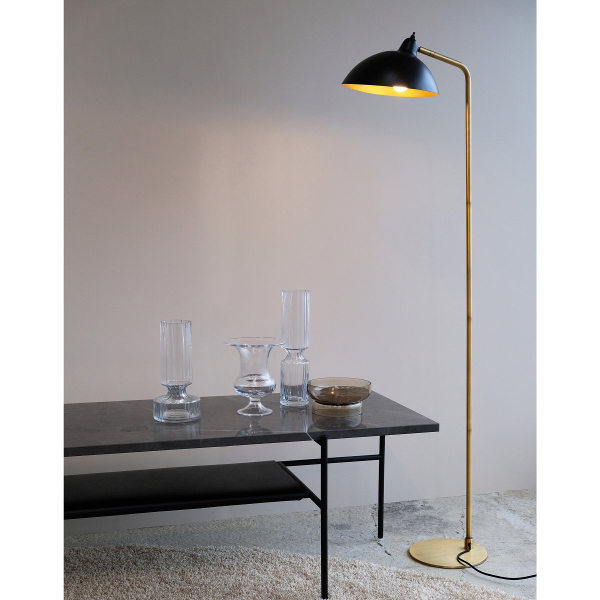 Futura Messing vloerlamp Van Dyberg Larsen - Het zwarte oppervlak en de antieke messingkleurige binnenkant van de lampenkap verspreiden een warm licht en cre&euml;ren een gezellige sfeer in huis.