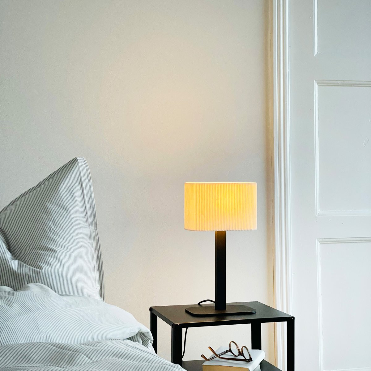 Calix Ovaal 40cm Zwart tafellamp Van Dyberg Larsen - Den ribbade, naturf&auml;rgade sk&auml;rmen av textil medf&ouml;r en v&auml;rme till rummet och i kombination med den svarta metallfoten passar Calix in i alla stilar och hem.