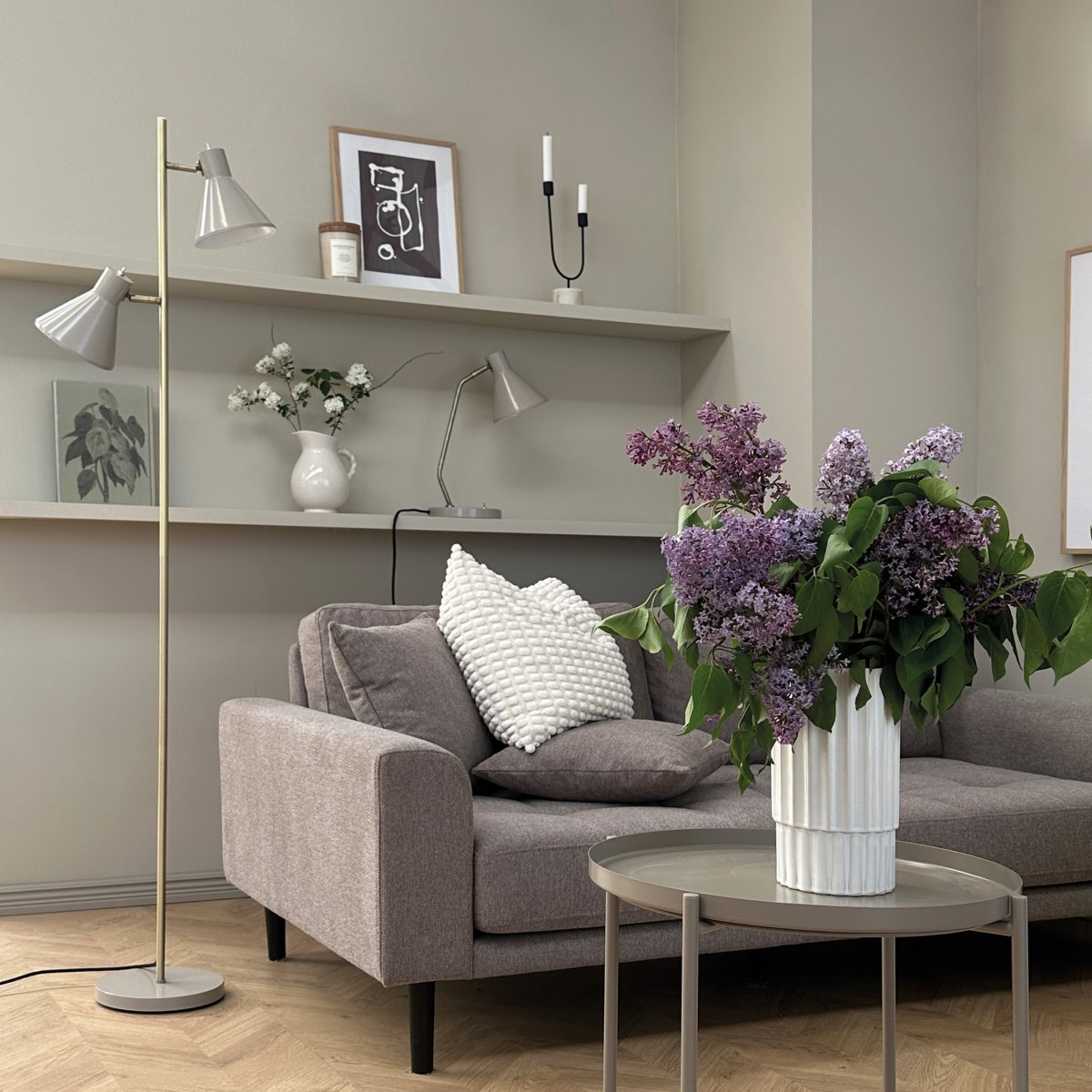 Sleep Glanzend beige vloerlamp Van Dyberg Larsen - De beige kleur geeft de lamp een moderne en strakke uitstraling die past bij verschillende interieurstijlen, terwijl de antieke messing details een elegante toets toevoegen.