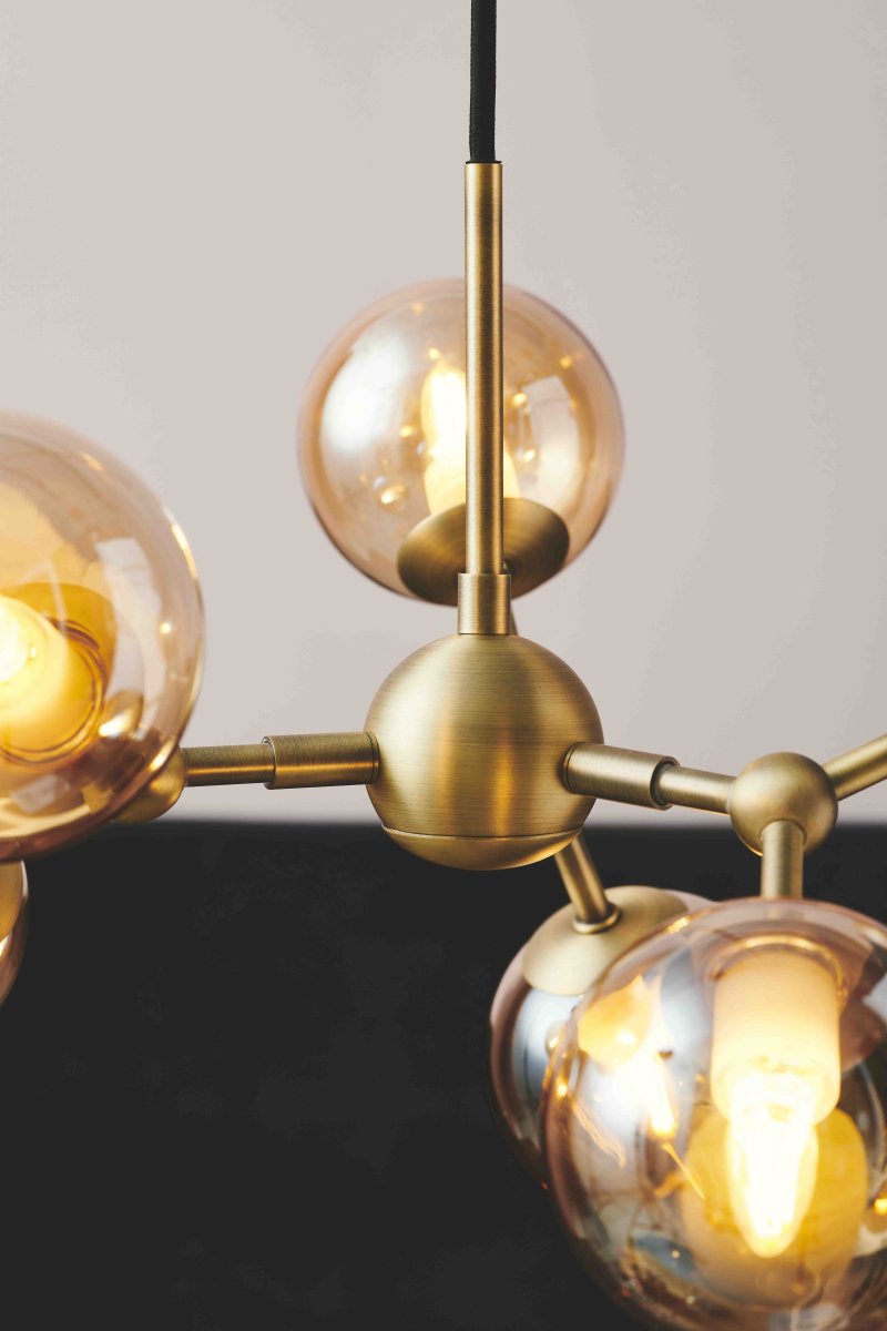 Atom 45cm Antiek messing hanglamp Van Halo Design - De bijna zwevende glazen koepels zijn amberkleurig, waardoor er een mooie lichtspreiding in de ruimte ontstaat.