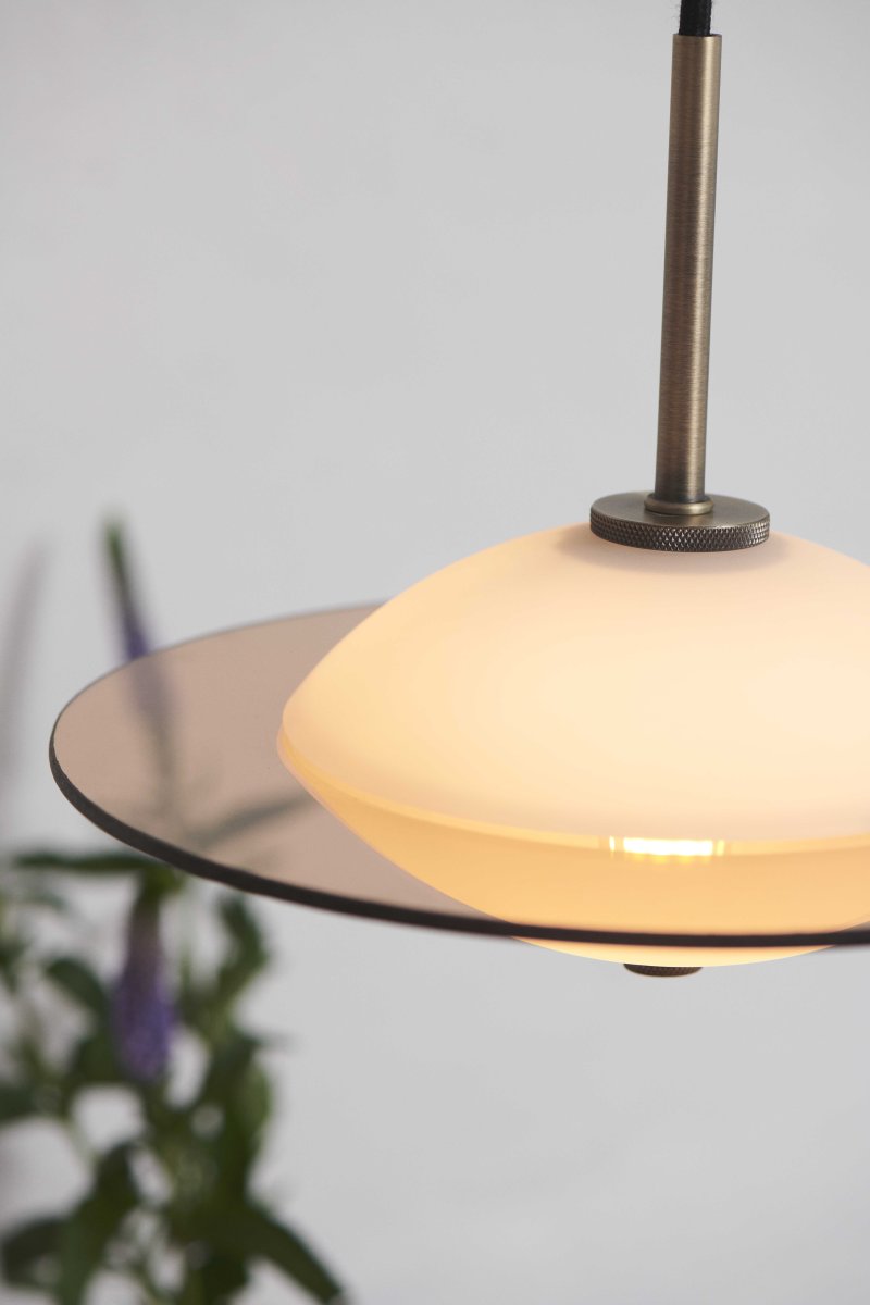 Orbit Ø24 Antiquiteit hanglamp Van Halo Design - De ronde vorm van opaalglas zorgt voor een zacht en sfeervol licht, terwijl de details in antiek messing en amberkleurig glas een warme en verfijnde toets toevoegen.