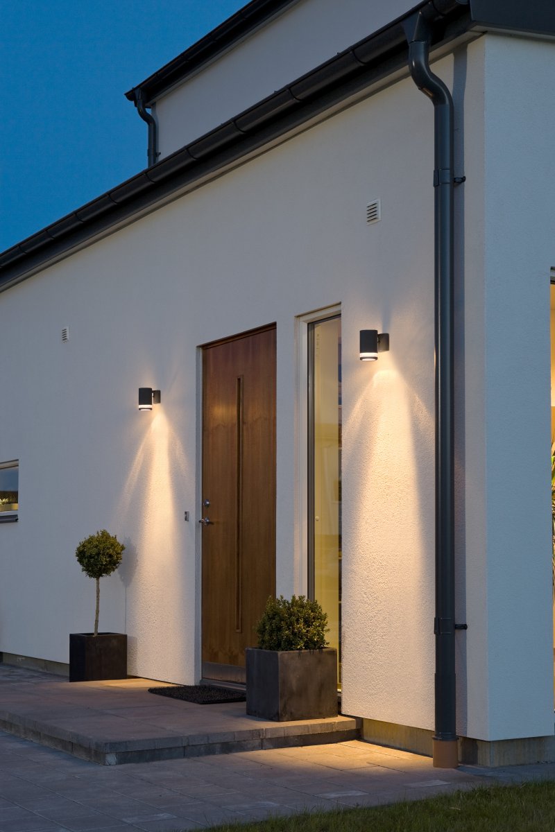 Modena Zwart buitenlamp Van Konstsmide - Modena is een stijlvolle gevellamp van zwart gelakt aluminium met een elegant detail van transparant acrylglas, wat de lamp een moderne uitstraling geeft.