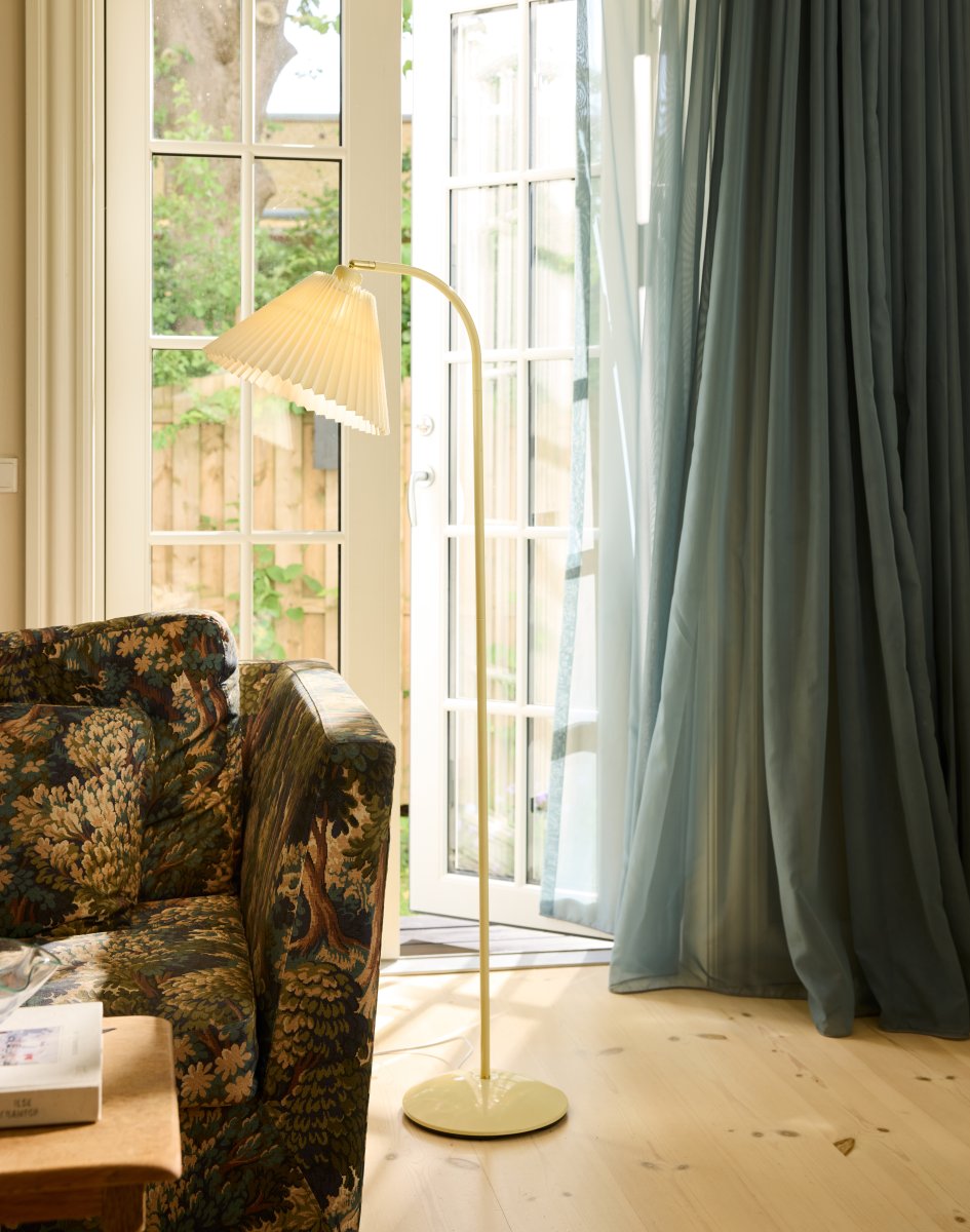 Medina Crème wit vloerlamp Van Halo Design - Het crèmekleurige metalen frame wordt aangevuld door een prachtige geplooide textielen kap in een bijpassende tint en decoratieve details van messing.
