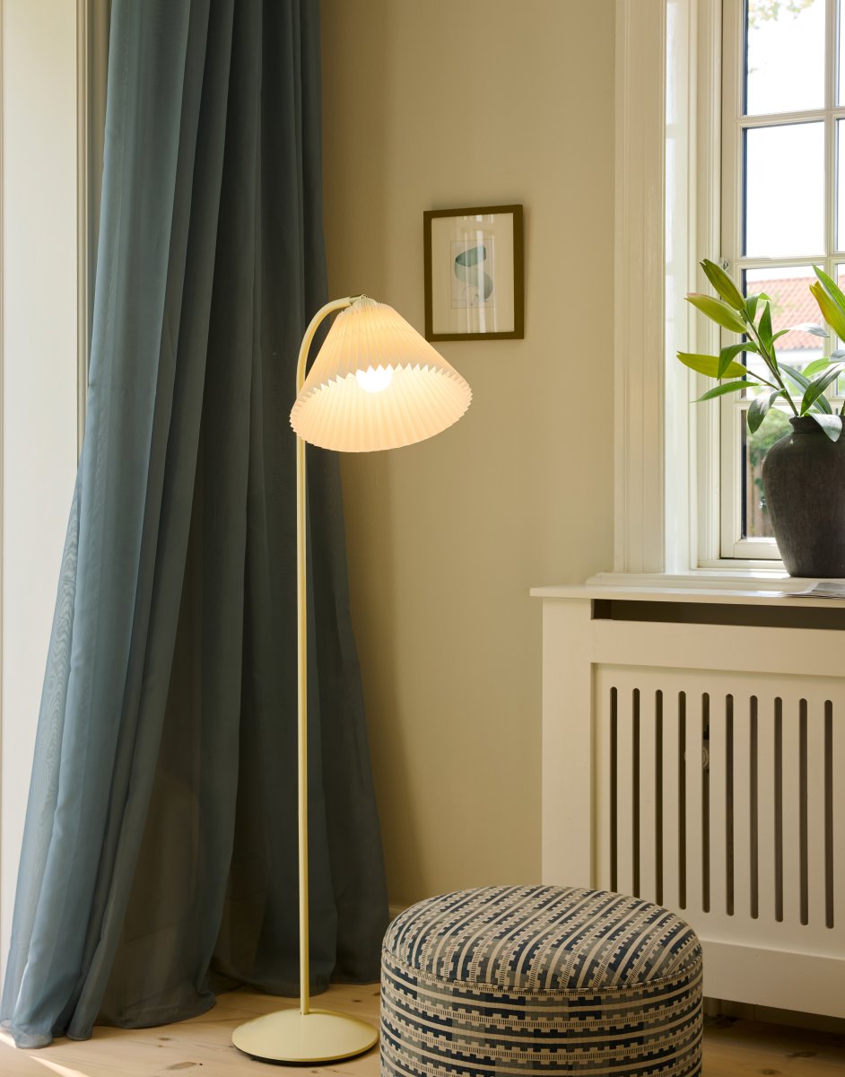 Medina Crème wit vloerlamp Van Halo Design - Het crèmekleurige metalen frame wordt aangevuld door een prachtige geplooide textielen kap in een bijpassende tint en decoratieve details van messing.
