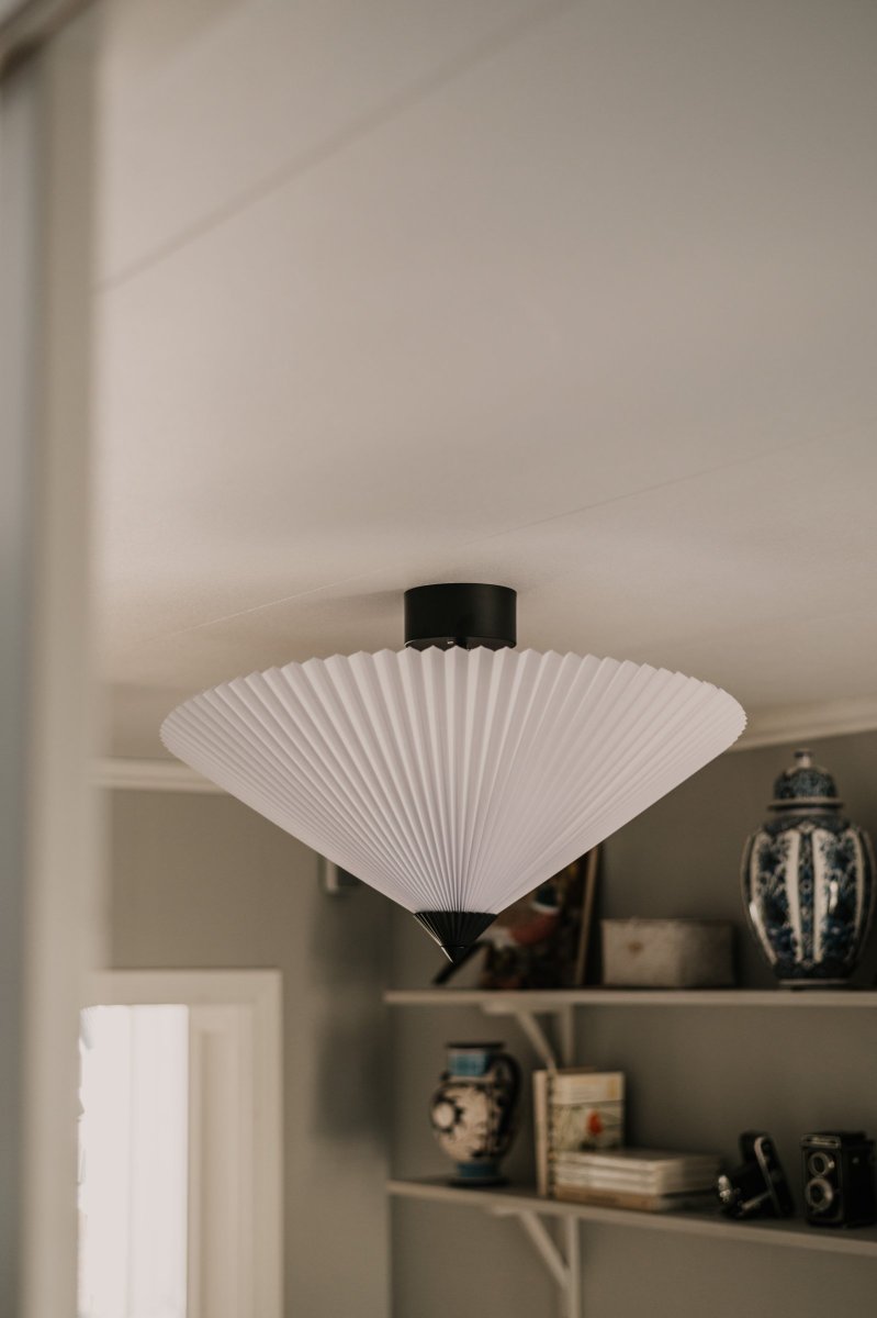 Matisse Ø60 Wit plafondlamp Van Globen Lighting - De lampenkap hangt aan een matzwarte metalen stang die op een plafondkap in bijpassende kleur is gemonteerd.