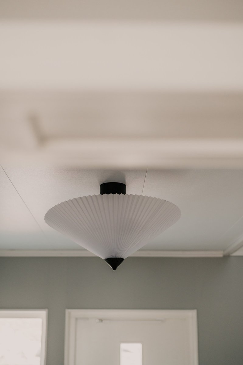 Matisse Ø60 Wit plafondlamp Van Globen Lighting - De lampenkap hangt aan een matzwarte metalen stang die op een plafondkap in bijpassende kleur is gemonteerd.