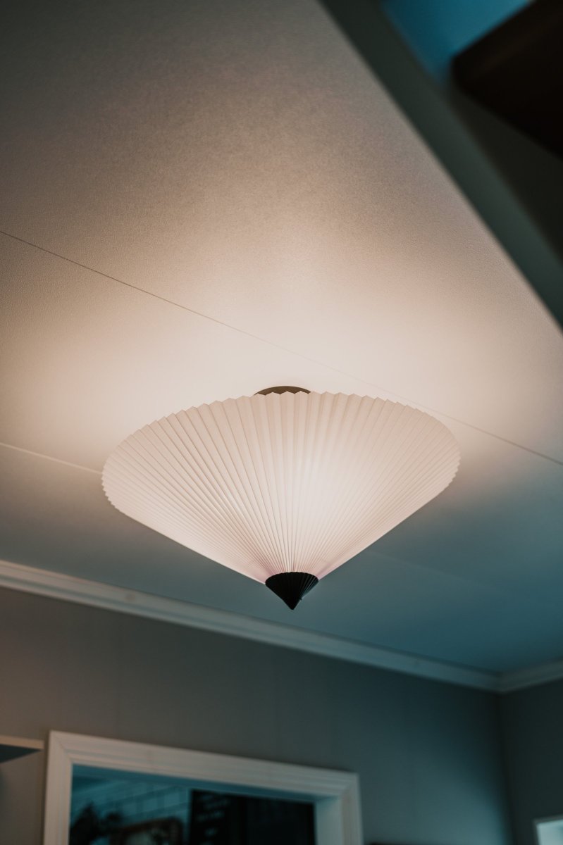 Matisse Ø60 Wit plafondlamp Van Globen Lighting - De lampenkap hangt aan een matzwarte metalen stang die op een plafondkap in bijpassende kleur is gemonteerd.