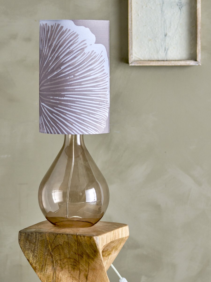 Leni 65cm Paars tafellamp Van Bloomingville - De organisch gevormde lampenvoet van bruin glas geeft een luchtige en elegante indruk, terwijl de cilindrische lampenkap met een paarse tint versierd is met een wit bloemenpatroon dat charme en persoonlijkheid toevoegt.
