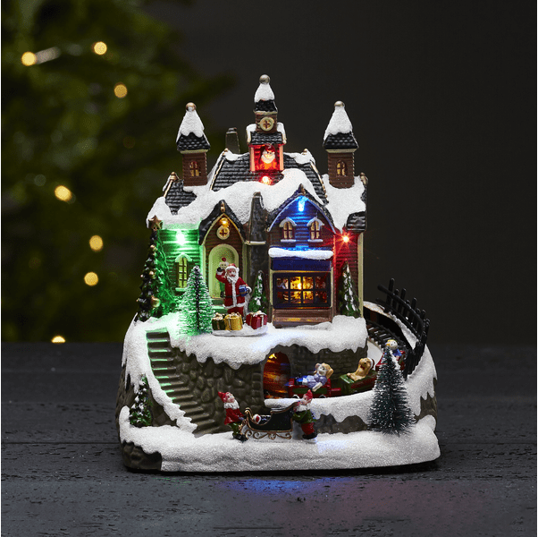 Trainville Veelkleurig Van Star Trading - Decoratief kerstdorp bestaande uit huizen met torens, heldere en luidruchtige ramen en een staande en zwaaiende Kerstman.