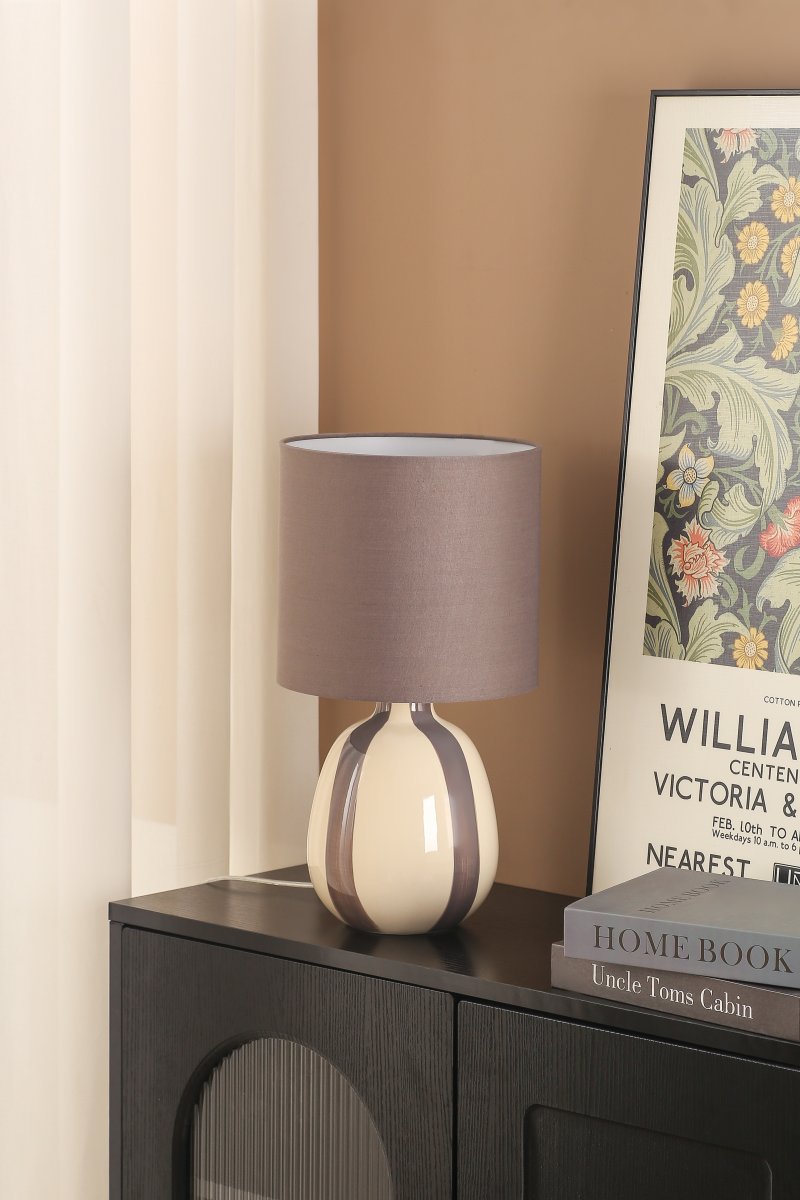 Rippel 40cm Grijs tafellamp Van Nordic Lighting - De lampvoet is gemaakt van keramiek met een cr&egrave;mekleurige basis en grijze strepen die een levendige maar zachte uitstraling geven.